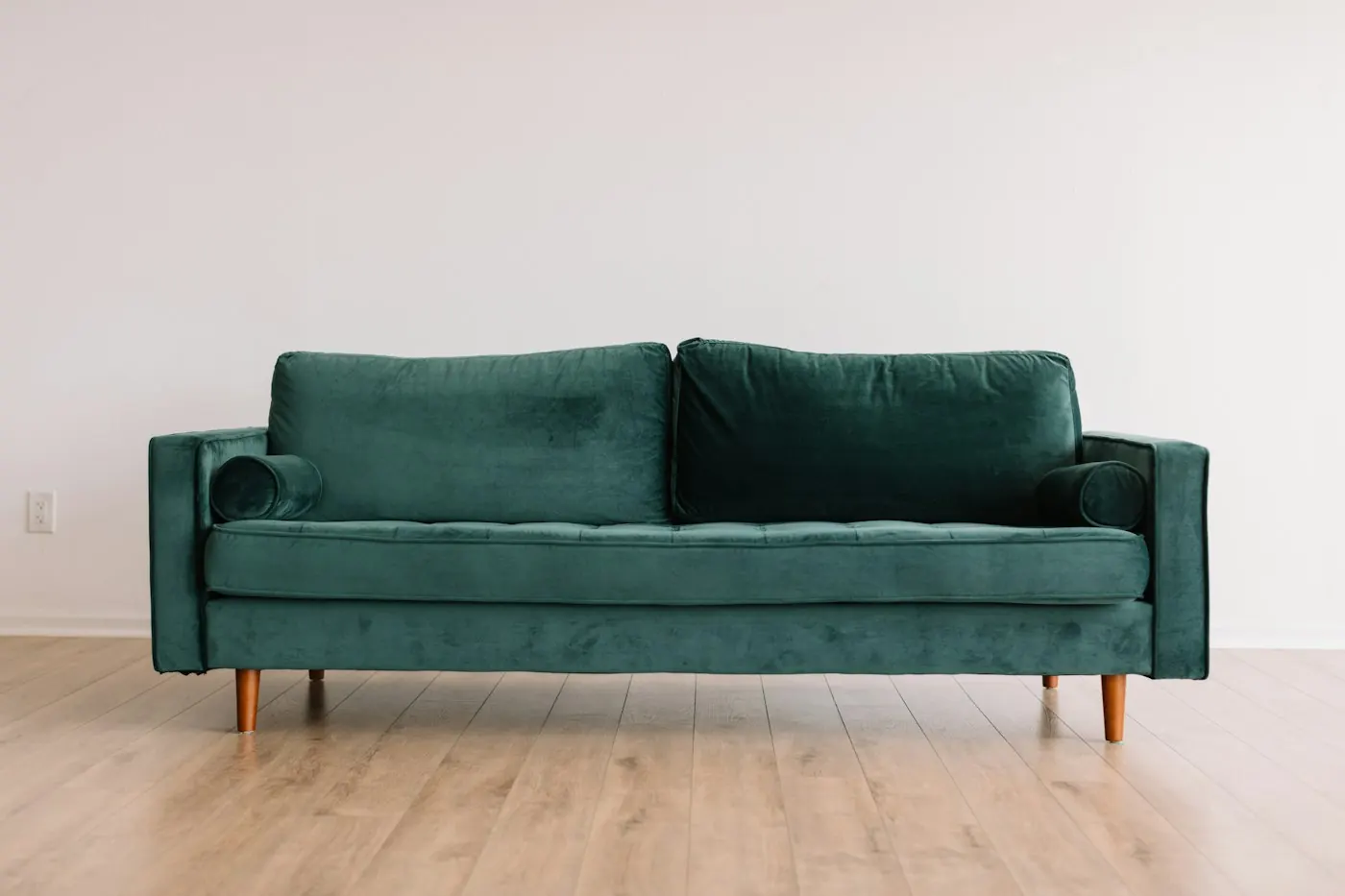 Salon avec un divan vert devant un mur